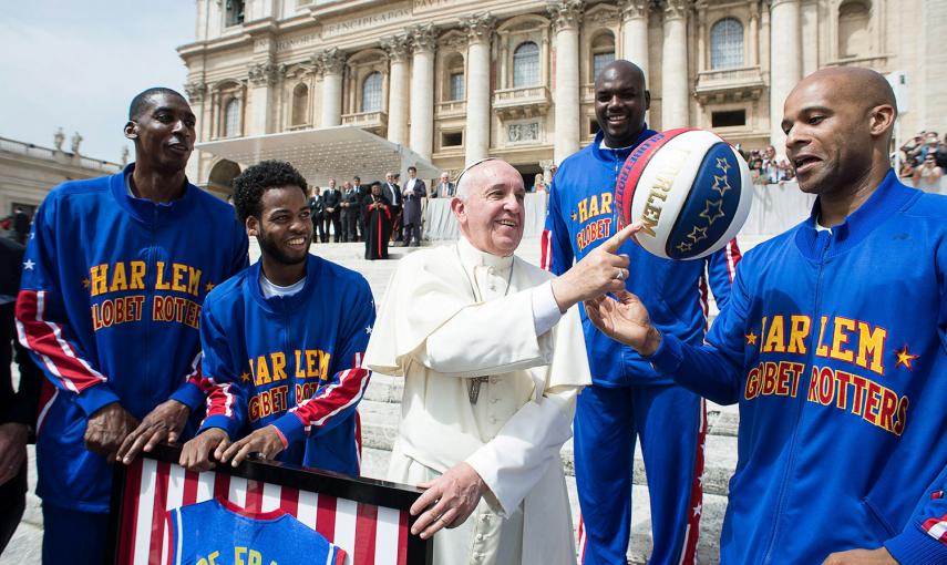 El Papa Francisco sonríe mientas juega con una pelota de baloncesto junto a un miembro del equipo de baloncesto Harlem Globotrotters en la plaza de San Pedro, en el Vaticano.- OSSERVATORE ROMANO / REUTERS