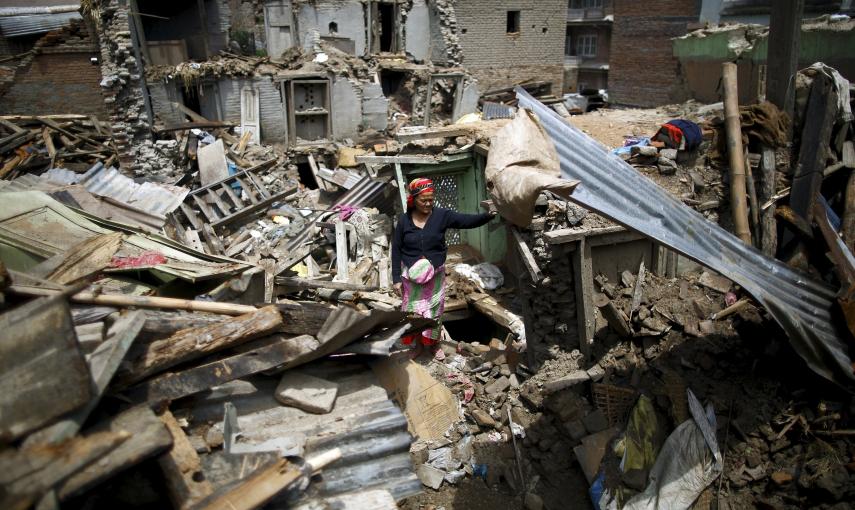Una mujer permanece entre los escombros de uno de los edificios derruidos en la ciudad de Sankhu. - REUTERS