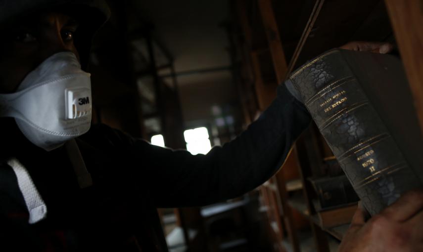 Un activista observa libros antiguos almacenados en el edificio okupado en Madrid.- JAIRO VARGAS