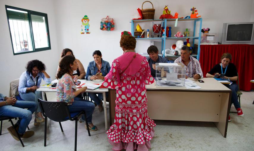 Una mujer vestida con el traje tradicional de rociera, en un colegio electoral, durante las elecciones del 24-M en El Rocío.- MARCELO DEL POZO (REUTERS)