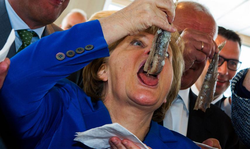 La canciller alemana Angela Merkel se come un arenque en Sassnitz, Alemania del este.- JENS BATTNER (AFP)