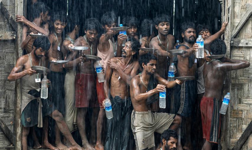 Varios inmigrantes recogen el agua de lluvia en un campo de refugiados en Birmania.- SOE ZEYA TUN (REUTERS)