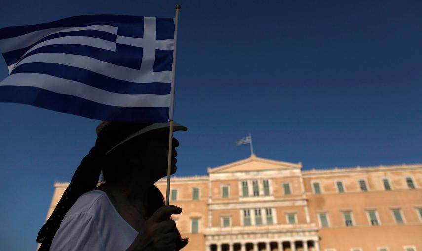 Una manifestante sostiene una bandera griega en frente del Parlamento.-Yannis Kolesidis (EFE)