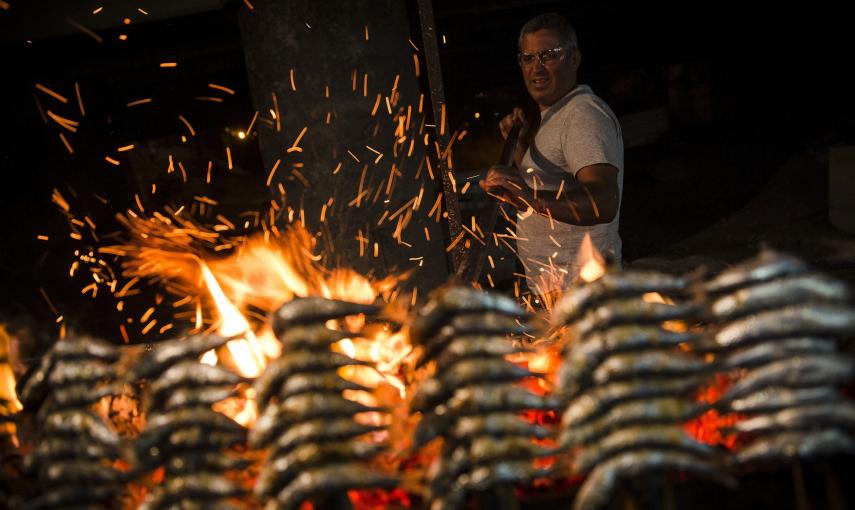 Un hombre prepara unos espetos junto a una hoguera durante las celebraciones de la noche de San Juan en la playa del Rincón de la Victoria, en Málaga. EFE/Jorge Zapata