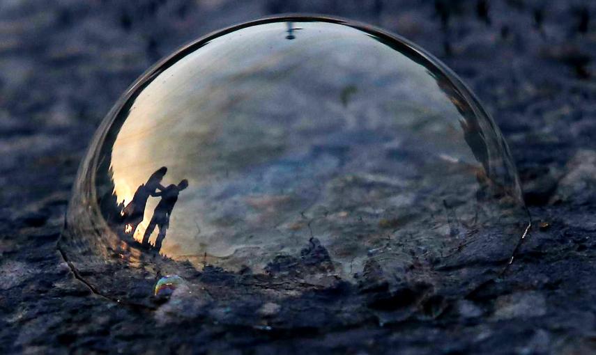 La gente, reflejada en una burbuja de jabón en la carretera, durante la noche e Nueva Delhi.- ANINDITO NUKHERJEE (REUTERS)