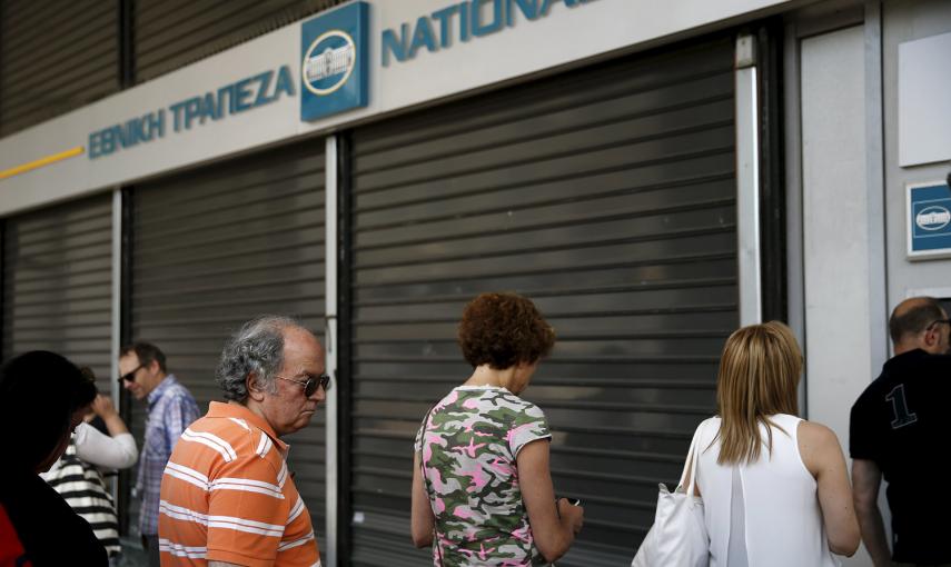 La gente hace cola en un cajero automático  del Banco Nacional en Atenas. Tras el anuncio del referéndum para aceptar o no las medidas exigidas por los acreedores, las sucursales han cerrado y el BCE ha dejado de inyectar liquidez a los bancos griegos. Lo