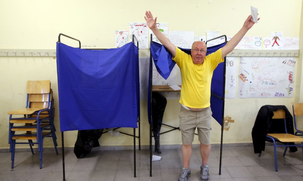 Un hombre saluda victorioso al salir de la cabina de votación de un colegio de Atenas. REUTERS/Jean-Paul Pelissie