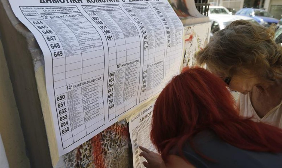 Varias personas intentan encontrar sus nombres en las listas de votación del referéndum griego en un colegio de Atenas. EFE/EPA/Armando Babani