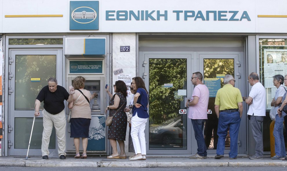 Algunos atenientes hacen cola en un cajero -el límite de 60 euros por día sigue vigente- donde lucen carteles a favor del 'No' en referéndum. REUTERS/Christian Hartmann