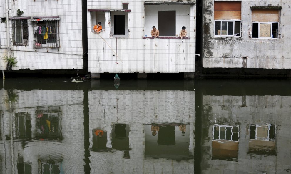 La gente pescando desde un piso abandonado en el pueblo de Xian, un barrio pobre en el centro de Guangzhou, China, 24 de julio de 2015. REUTERS / Tyrone Siu