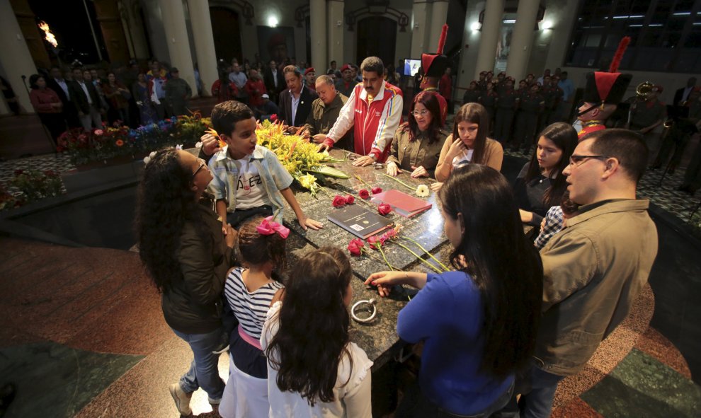 El presidente de Venezuela, Nicolás Maduro (C), junto a familiares del fallecido presidente Hugo Chávez, visitando su tumba durante una ceremonia para conmemorar su 61º cumpleaños en Caracas. Foto proporcionada por el Palacio de Miraflores. 2015.REUTERS /