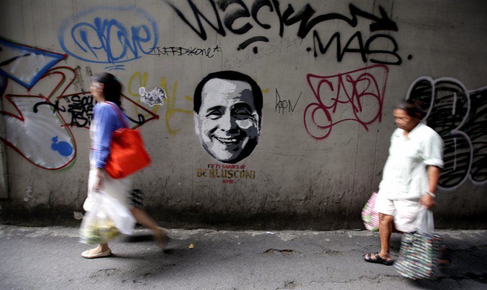Fotografía de hoy, miércoles 29 de julio de 2015, que muestra a peatones pasando frente a un grafitti que reza " 50 Sombras de Berlusconi" bajo el rostro del ex Primer Ministro italiano Silvio Berlusconi en las calles de Bangkok (Tailandia). EFE/BARBARA W