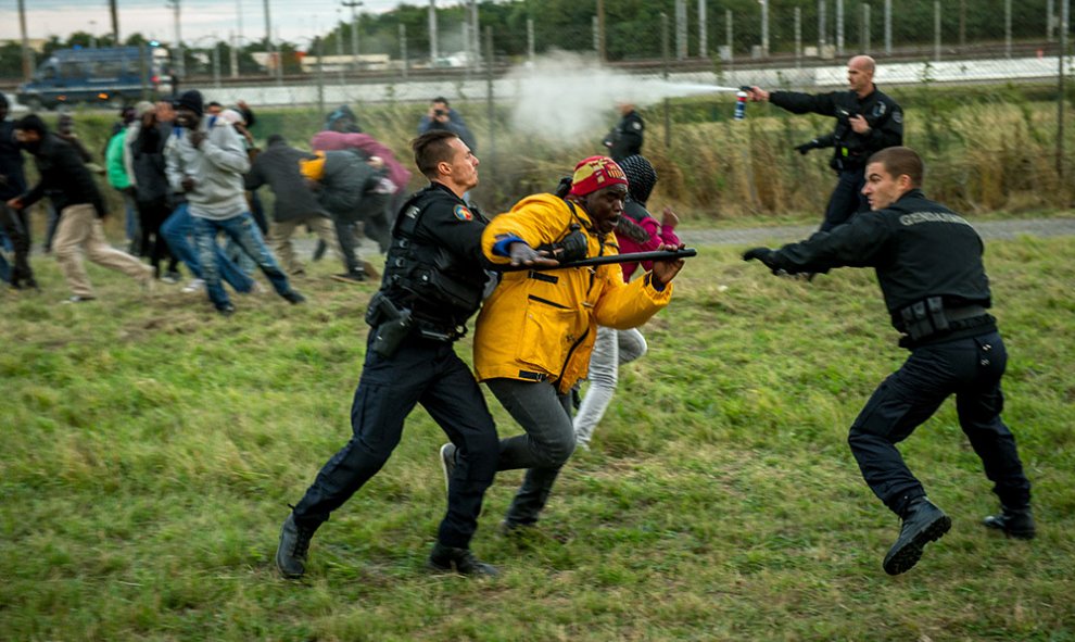 Gendarmes franceses tratan de detener inmigrantes que intentan cruzar el Eurotunel camino a Inglaterra.- PHILIPPE HUGUEN (AFP)