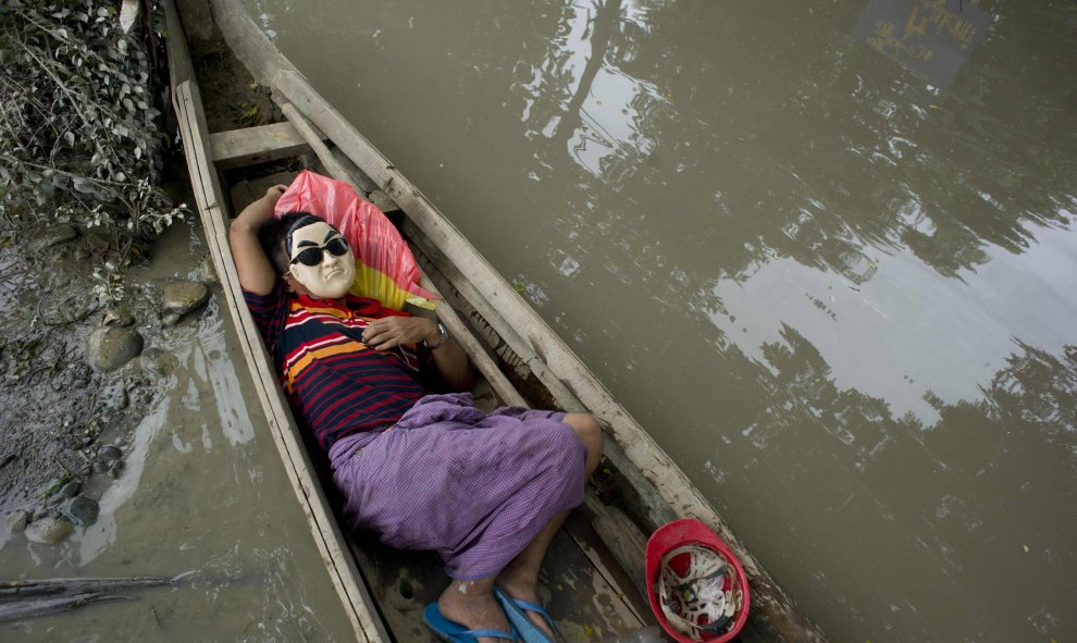 Un residente descansa en una barca junto en las aguas de Kalay, en la región de Sagaing de Myanmar, el 3 de agosto de 2015. Las lluvias monzónicas han provocado inundaciones repentinas y deslizamientos de tierra, destruyendo miles de casas, tierras de cul