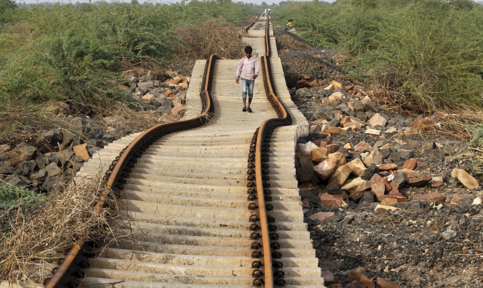 Un aldeano camina sobre las vías del tren que fueron dañadas por las fuertes lluvias monzónicas cerca de la aldea Patdi en Gujarat, 3 de agosto de 2015. REUTERS / Dave Amit