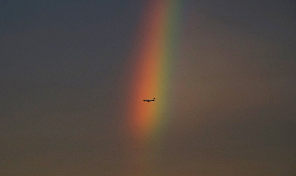 Un avión vuela más allá de un arco iris en la oscuridad en Beijing, China.-REUTERS / Guo Guanglin