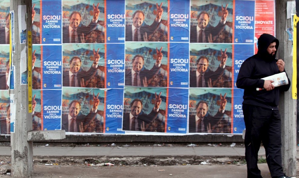 Un hombre en una parada de autobús junto a los carteles que anuncian el candidato presidencial Scioli en La Matanza, Argentina. REUTERS / Marcos Brindicci