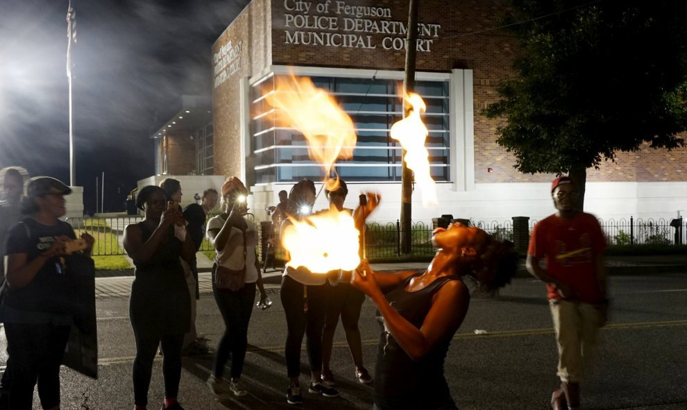 Laura Charles realiza juegos con palos de fuego durante una protesta fuera del departamento de policía de Ferguson por el aniversario de los disturbios de Ferguson. REUTERS / Rick Wilking
