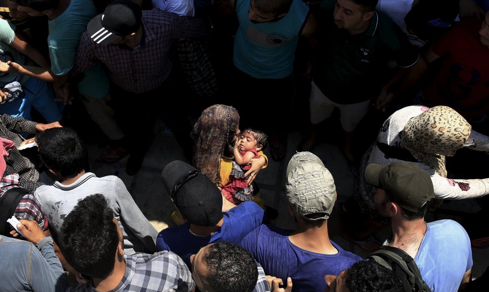 Hombres sirios forman una barrera de seguridad para las mujeres por los enfrentamientos durante un procedimiento de registro en el estadio nacional de la isla griega de Cos, 11 de agosto 2015./ REUTERS/ Yannis Behrakis