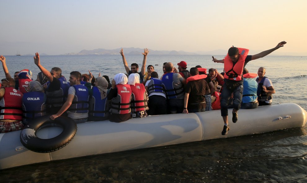 Refugiados sirios saltan de alegría al llegar a una playa en la isla griega de Cos, 11 de agosto de 2015.REUTERS/ Yannis Behrakis