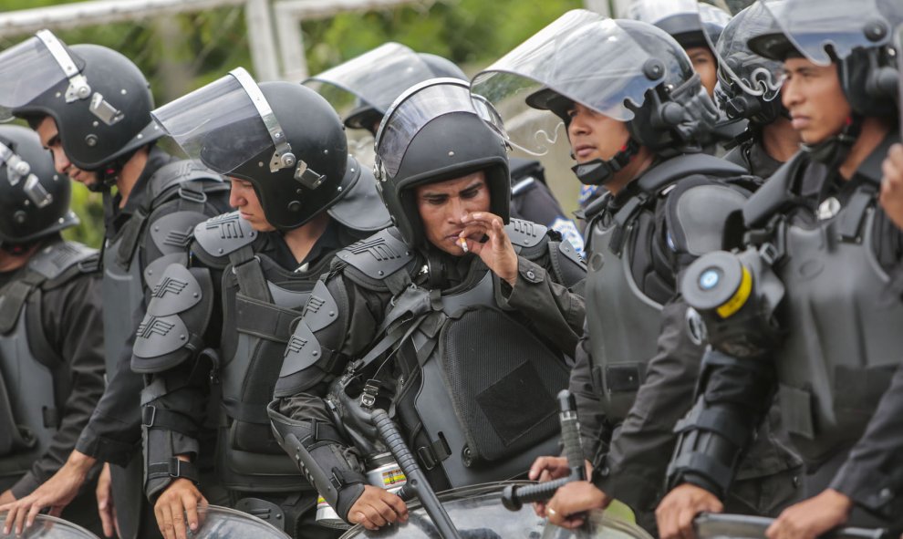 Un policía antidisturbios fuma un cigarrillo durante una protesta contra el sistema electoral, en Managua, el 12 de agosto de 2015. AFP PHOTO / Inti OCON