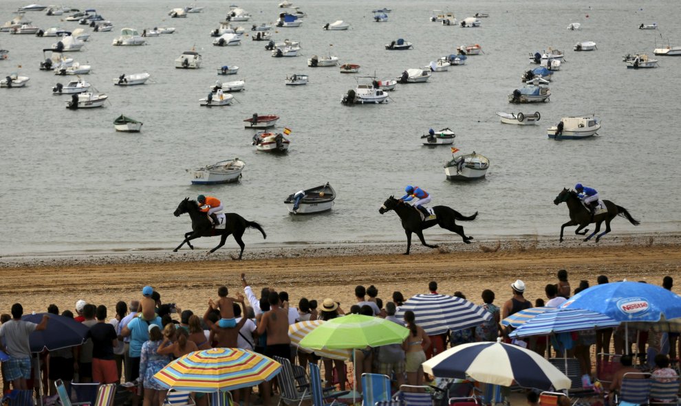 Jinetes cabalgan durante una tradicional carrera por la playa de Sanlúcar de Barrameda, en el sur de España, 12 de agosto de 2015. REUTERS / Marcelo del Pozo