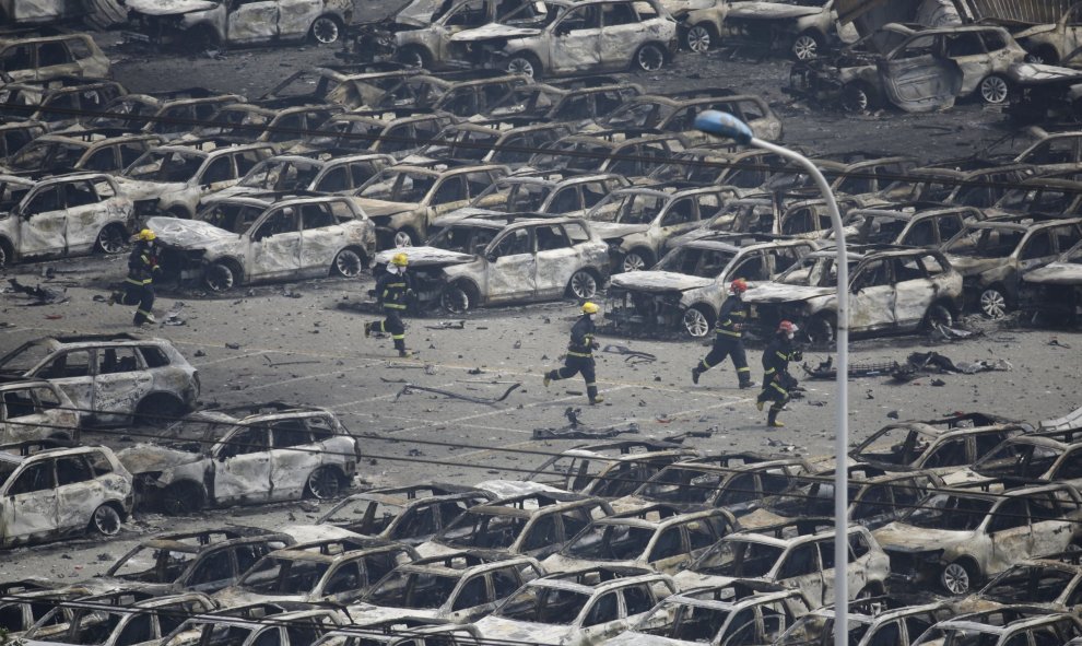 Los bomberos corren como entre coches calcinados en el lugar de las explosiones que han causado decenas de muertos en la ciudad de Tianjin, China.- REUTERS / Jason Lee