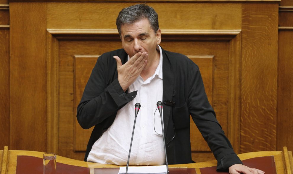 El ministro de Finanzas griego, Euclides Tsakalotos, bosteza mientras varios diputados intentan interrumpir su discurso en un debate que se prolongó durante toda la noche para aprobar el tercer rescate a Grecia.-REUTERS / Christian Hartmann