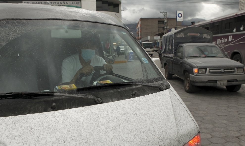 Un hombre lleva mascarilla mientras conduce su coche cubierto de ceniza volcánica en Machachi./ REUTERS