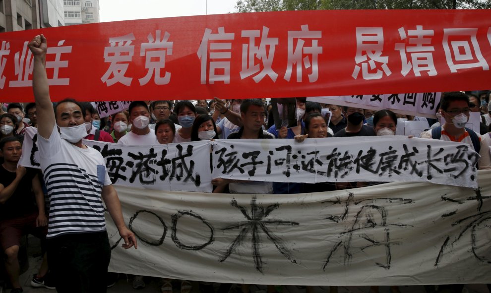 Los manifestantes portan una pancarta (la blanca) que reza: "Nuestros hijos preguntan: ¿Podemos todavía crecer sanos?". REUTERS