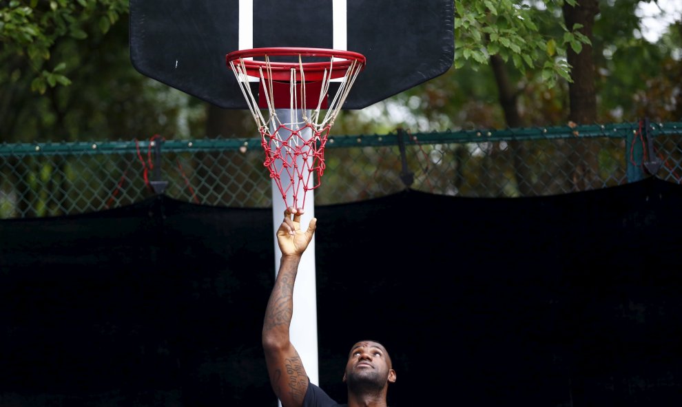 Jugador de baloncesto de la NBA LeBron James tira de una red durante un acto promocional de baloncesto en Shanghái, 17 de agosto de 2015. REUTERS / Aly Song