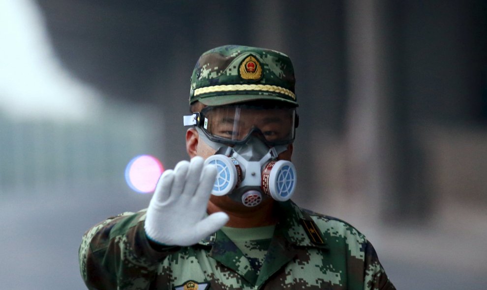 Un policía paramilitar que lleva una máscara de gestos al fotógrafo para dejar como él bloquea una carretera que conduce a la zona residencial evacuadas y lugar de la explosión, en el nuevo distrito de Binhai en Tianjin, China, 17 de agosto de 2015. REUTE