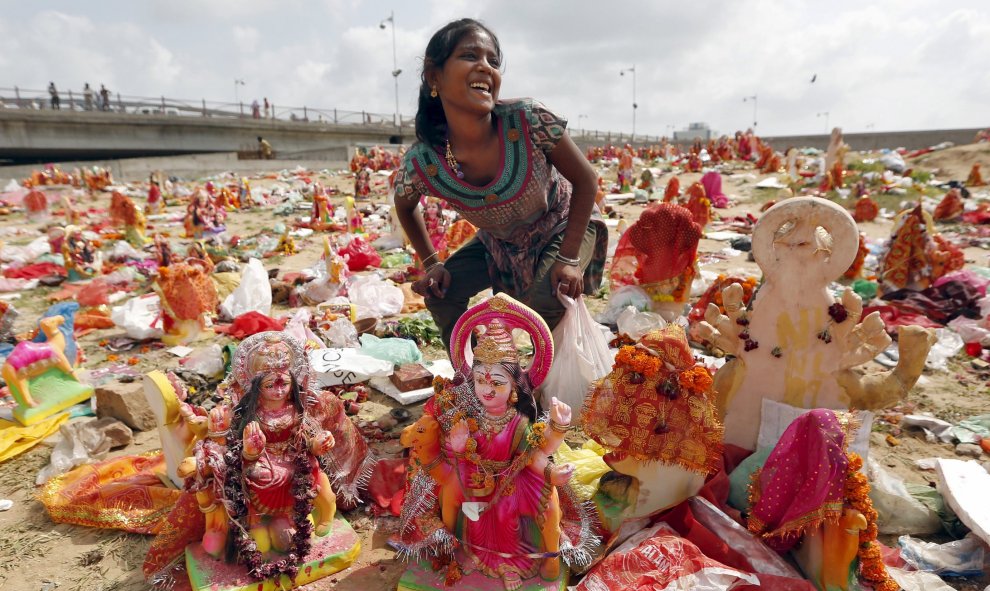 Una mujer recoge figuras de la diosa hindú Dashama, dejados por los devotos a orillas del río Sabarmati en el décimo y último día del festival dashama en Ahmedabad, India, 24 de agosto de 2015. REUTERS / Dave Amit