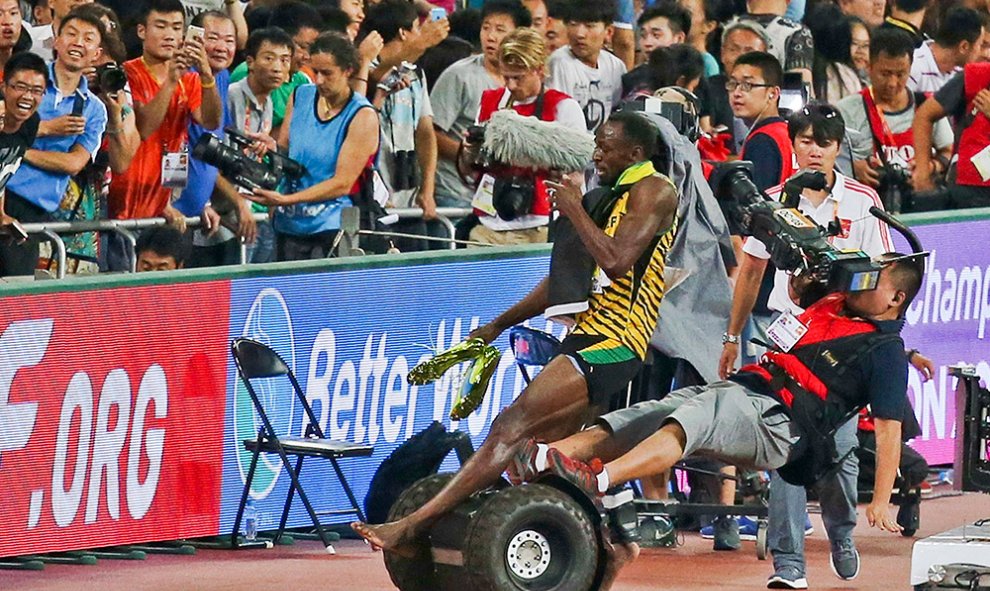 Usain Bolt es derribado por un cámara de televisión que perdió el control de su Segway. El accidente tuvo lugar después de que el jamaicano ganara la final de los 200 metros durante los campeonatos del mundo de atletismo en Pekín (China).- REUTERS/STR