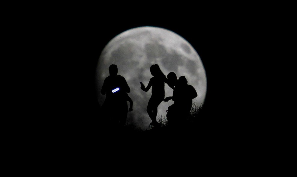 La silueta de grupo de excursionistas recortada ante la Luna, en Tijuana, México.- JORGE DUENES (REUTERS)