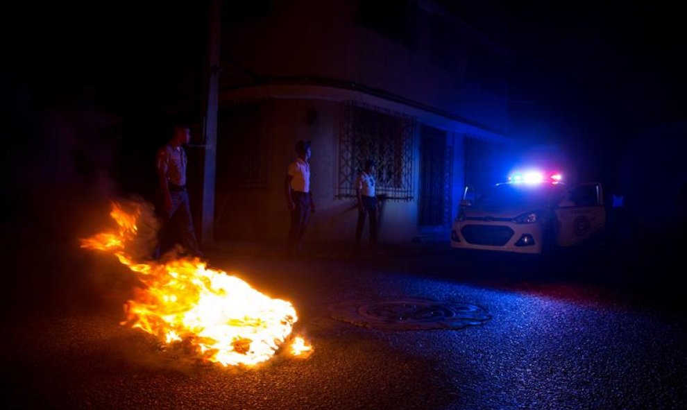 Policías dominicanos apagan una barricada encendida en protesta por el extenso apagón, debido a que el 85% del país se encuentra sin energía eléctrica tras el paso de la tormenta tropical Erika hoy, viernes 28 de agosto de 2015, en la zona colonial de Sa
