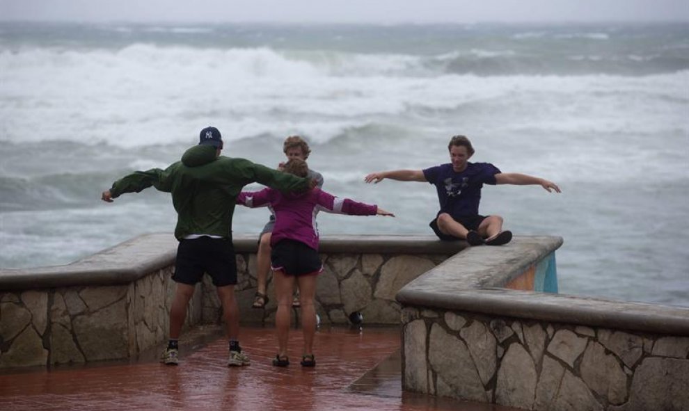 Jóvenes son vistos a la llegada de la tormenta tropical Erika hoy, viernes 28 de agosto de 2015, en Santo Domingo (República Dominicana). El centro de la tormenta tropical Erika se aproxima hoy al país mientras deja fuertes lluvias en Puerto Rico y las Is