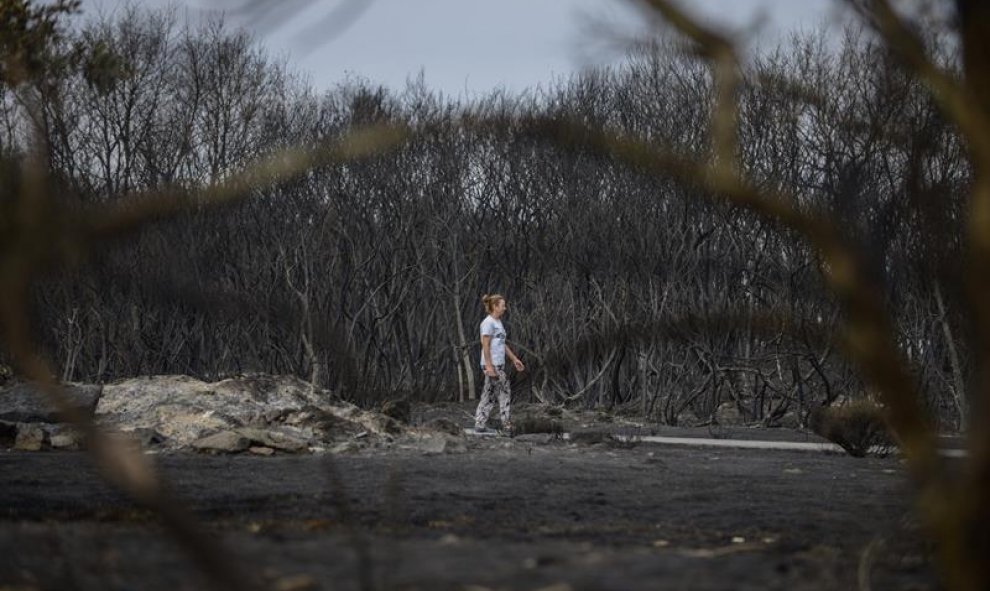 Una mujer camina por la superficie calcinada en la localidad de Vilela durante el incendio forestal de Cualedro ya estabilizado, que ha afectado a otros municipios de Ourense, y arroja un balance provisional de 3.000 hectáreas arrasadas, lo que lo convier