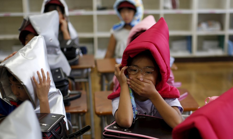 Niños se protegen con capuchas acolchadas en el simulacro de terremoto en un colegio de primaria en Tokio, 1 de septiembre, 2015. REUTERS/Toru Hanai