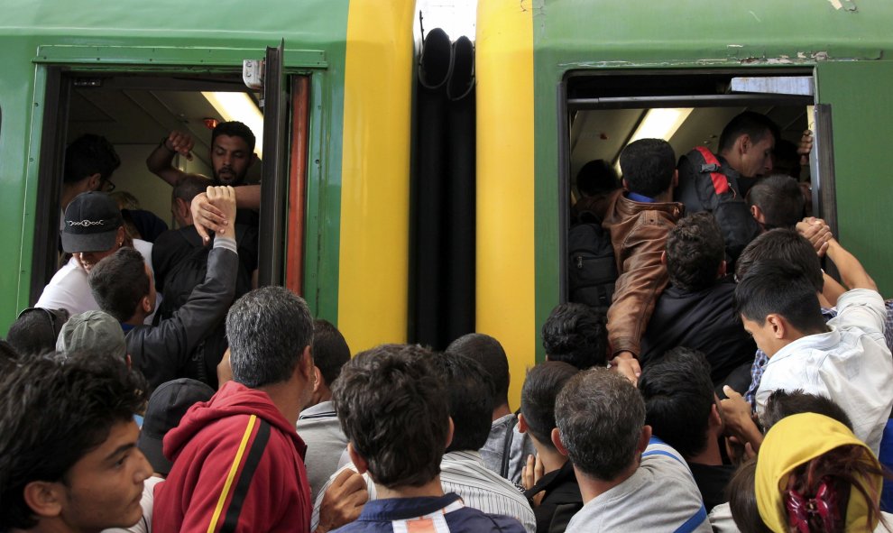 Decenas de refugiados intentan subirse a un vagón de tren entre empujones. /REUTERS