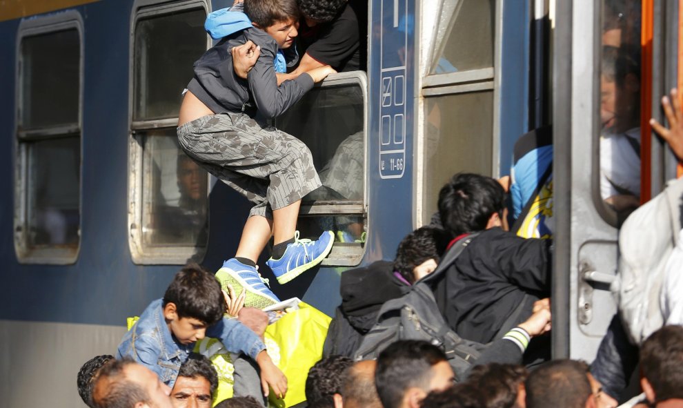 Un hombre, entre la multitud, intenta entrar a un tren por una ventana. /REUTERS