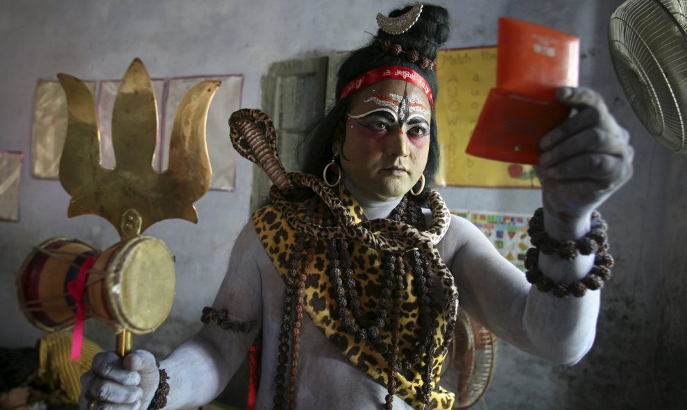 Un hombre vestido como un Shiva se mira en el espejo mientras se prepara para participar en una procesión religiosa en la víspera del festival de Janmashtami en Amritsar, India, 4 de septiembre de 2015. REUTERS / Munish Sharma