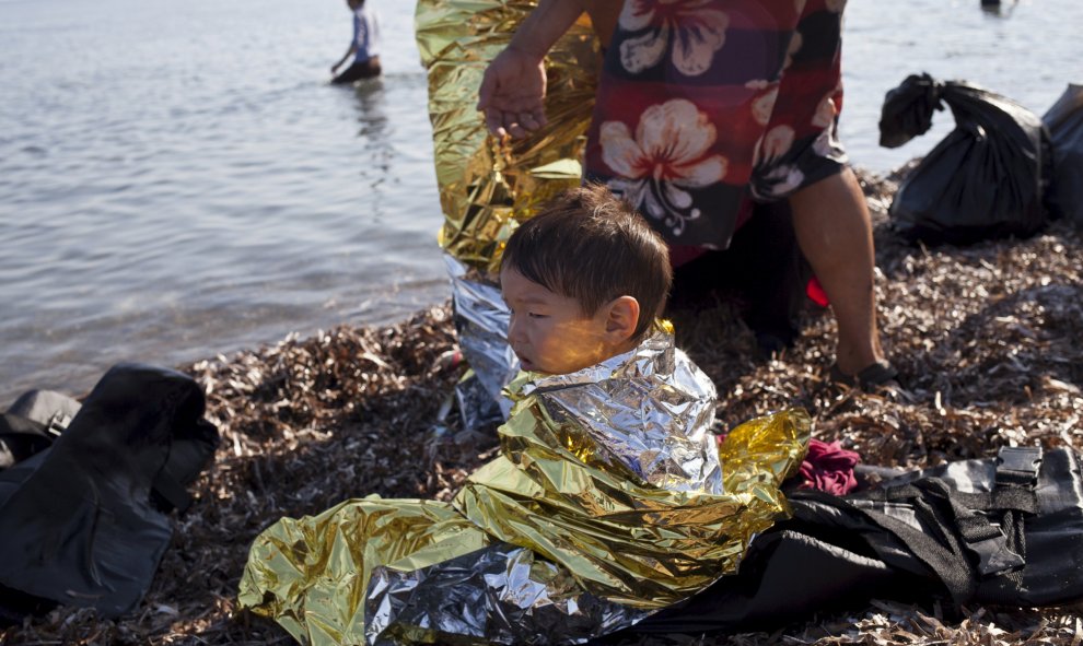 Niño afgano refugiado de 2 años lleva una manta térmica momentos después de llegar a la isla griega de Lesbos, 4, 2015. REUTERS / Dimitris Michalakis