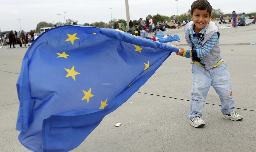 Un niño inmigrante juega con una bandera de la Unión Europea después de cruzar la frontera con Austria en Nickelsdorf, 5 de septiembre de 2015. REUTERS / Laszlo Balogh
