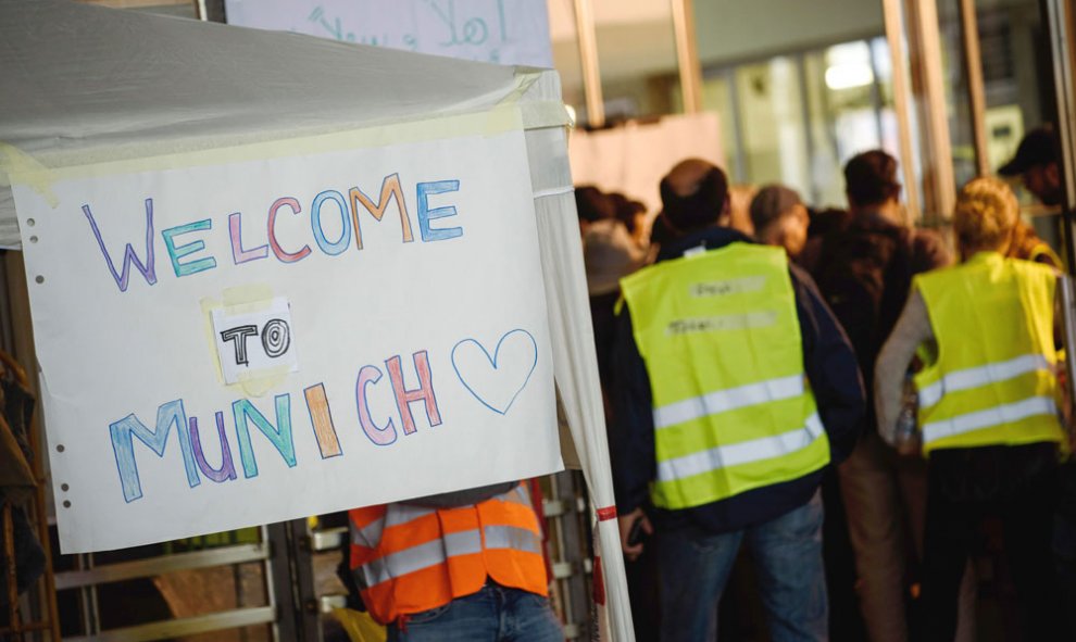 Voluntarios junto a un cartel con el texto "Bienvenidos a Múnich".- NICOLAS ARMER (EFE)