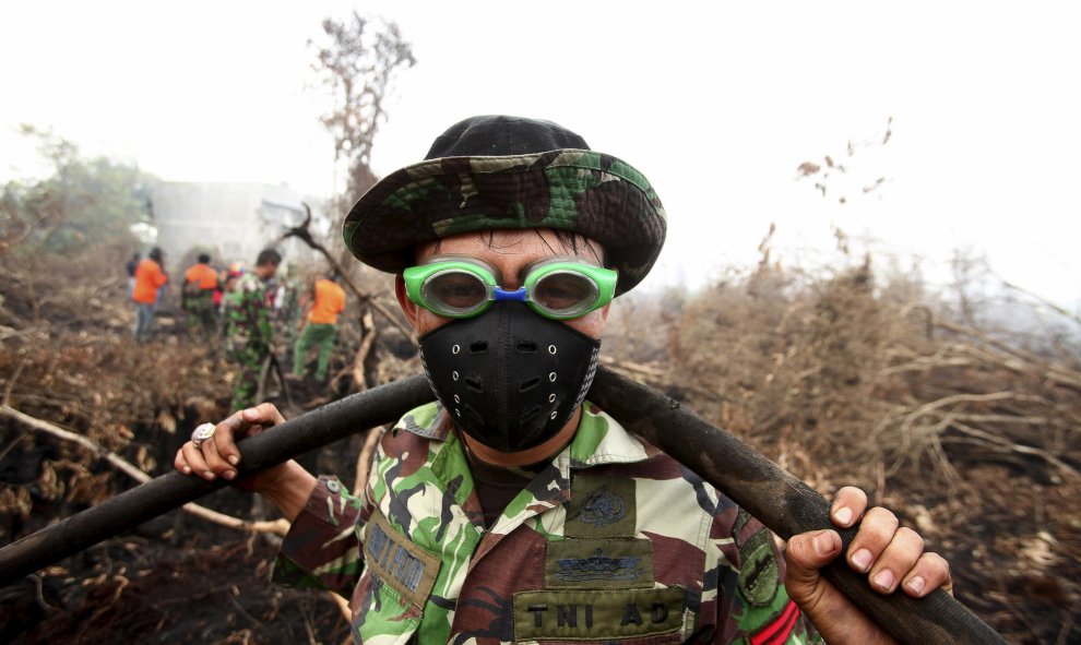 Un soldado indonesio utiliza gafas de natación para proteger sus ojos contra el humo mientras ayuda a apagar un incendio en una zona forestal de Parit Indah Village, Kampar, provincia de Riau, Indonesia, 8 de septiembre de 2015. REUTERS / YT Haryono