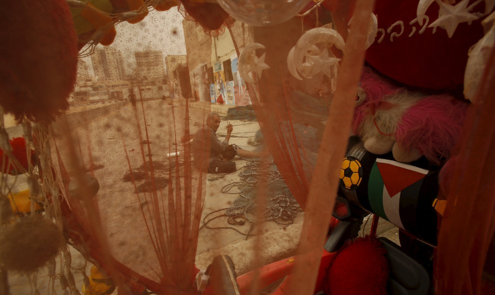 Se ve a un pescador palestino a través de una tela mientras prepara una red durante una tormenta de arena en el Puerto de la ciudad de Gaza, 9 de septiembre de 2015. REUTERS / Suhaib Salem