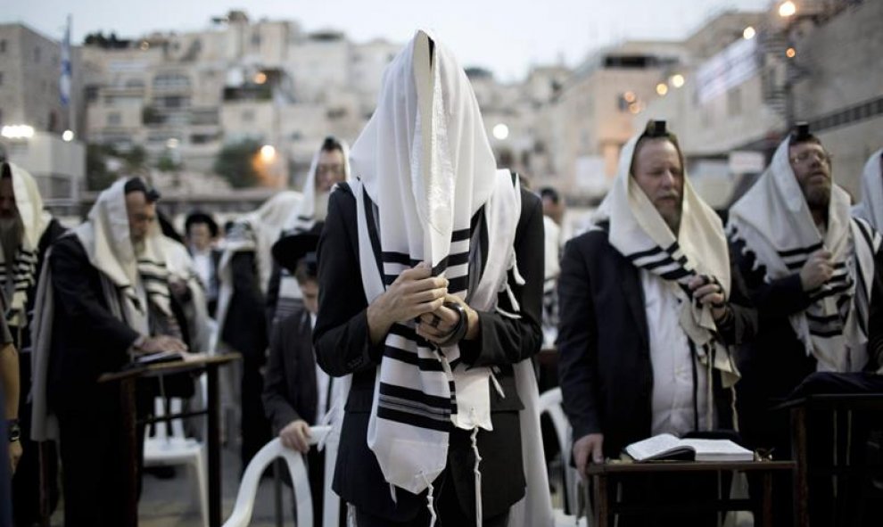 Judíos ortodoxos se cubren la cabeza con mantos de oración mientras rezan toda la noche por el perdón, o Selijot, en el Muro de las Lamentaciones. EFE / ABIR SULTAN