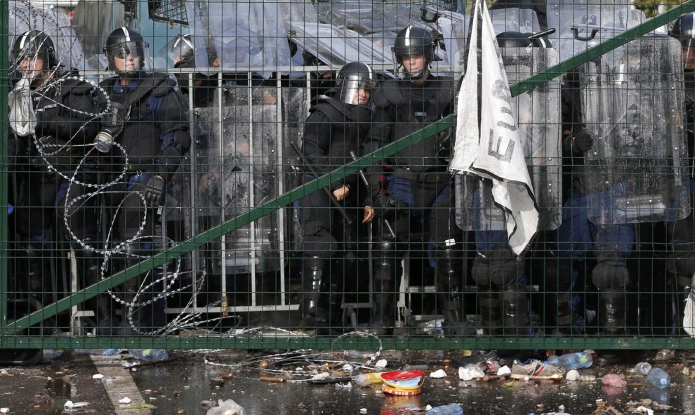 Agentes antidisturbios húngaros observan a los refugiados desde el otro lado de la frontera con Serbia. REUTERS