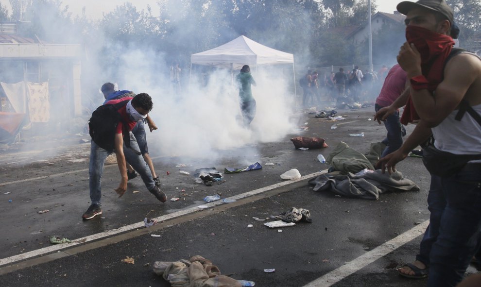 Migrantes se cubren la cara para protegerse de los gases lacrimógenos utilizados por la policía antidisturbios húngara en la parte serbia de la frontera, cerca de Röszke. REUTERS